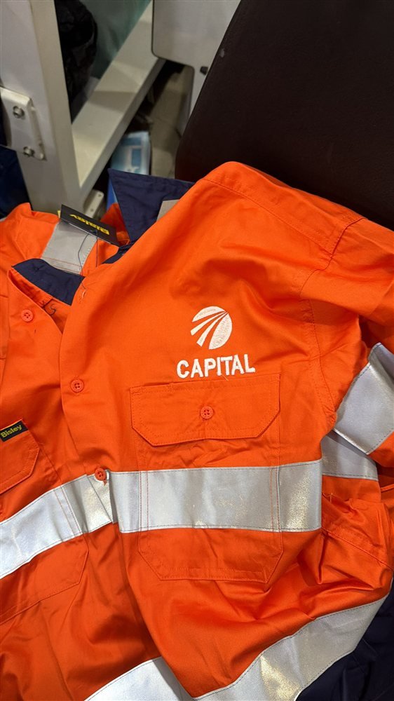 Logo d'entreprise brodé sur une chemise de travail orange