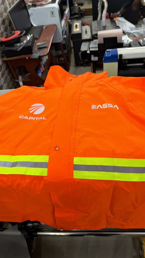 Gros plan sur une veste orange avec logo imprimé en DTF et bandes réfléchissantes